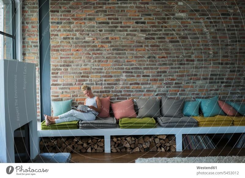 Mature woman sitting on couch, reading magazine home at home country house country houses cottage cottages Country Cottage settee sofa sofas couches settees