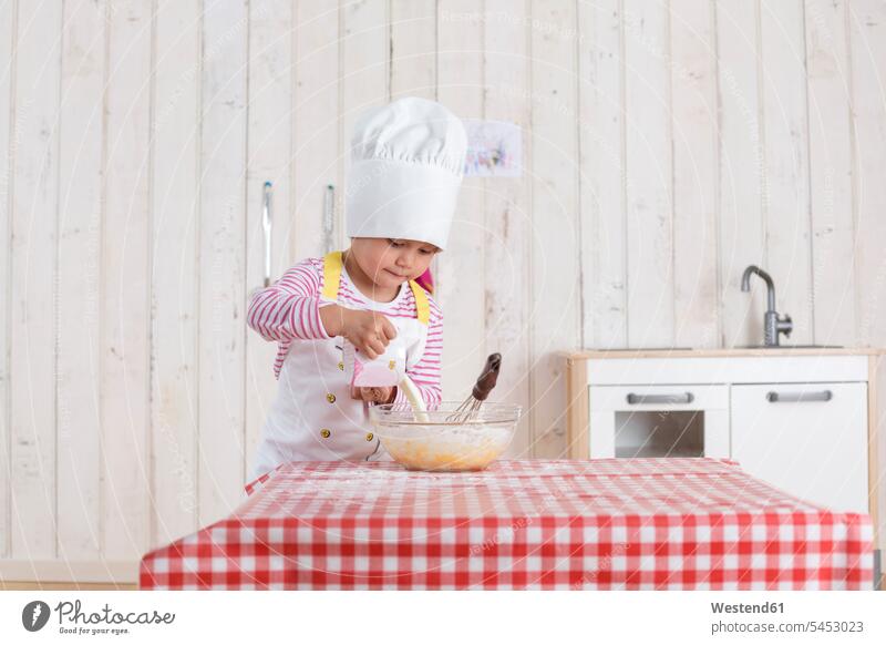 Little girl preparing waffles, wearing chef's hat kitchen females girls baking bake dough standing child children kid kids people persons human being humans