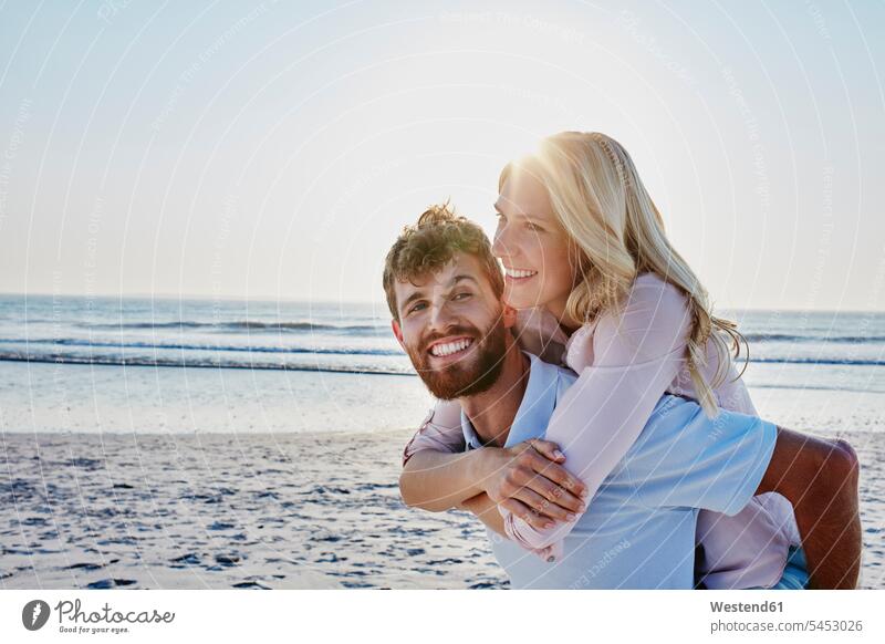 Portrait of happy couple on the beach smiling smile happiness twosomes partnership couples beaches piggyback piggy-back pickaback Piggybacking Piggy Back people
