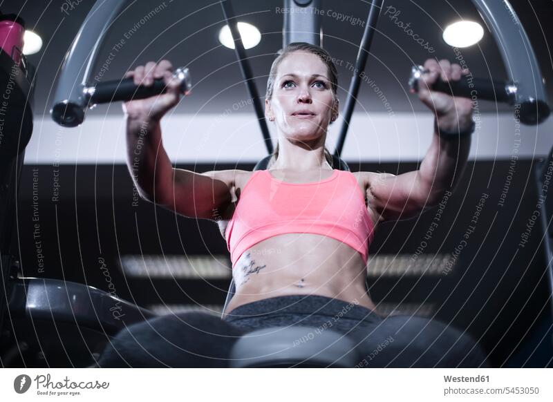 Focused woman using chest exercise equipment at gym females women gyms Health Club Adults grown-ups grownups adult people persons human being humans