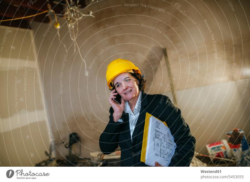 Woman wearing hard hat talking on phone on construction site on the phone call telephoning On The Telephone calling mobile phone mobiles mobile phones Cellphone