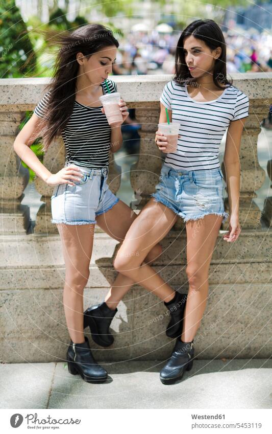 Two twin sisters outdoors having a takeaway drink Drink beverages Drinks Beverage female friends drinking food and drink Nutrition Alimentation Food and Drinks