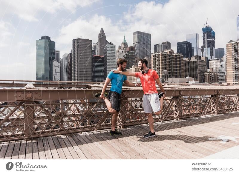 USA, New York City, two athletes stretching on Brooklyn Brige bridge bridges man men males friends Jogging headphones headset Adults grown-ups grownups adult