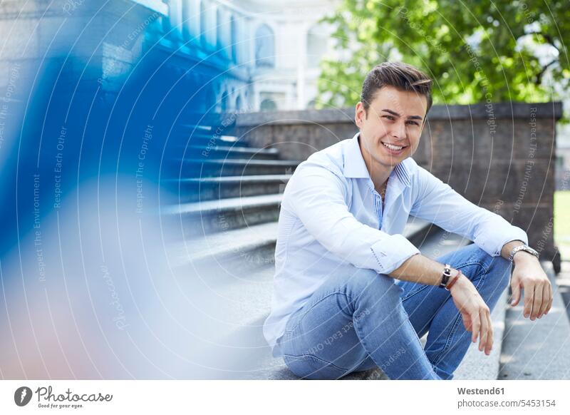 Portrait of smiling young man sitting on stairs portrait portraits men males Adults grown-ups grownups adult people persons human being humans human beings