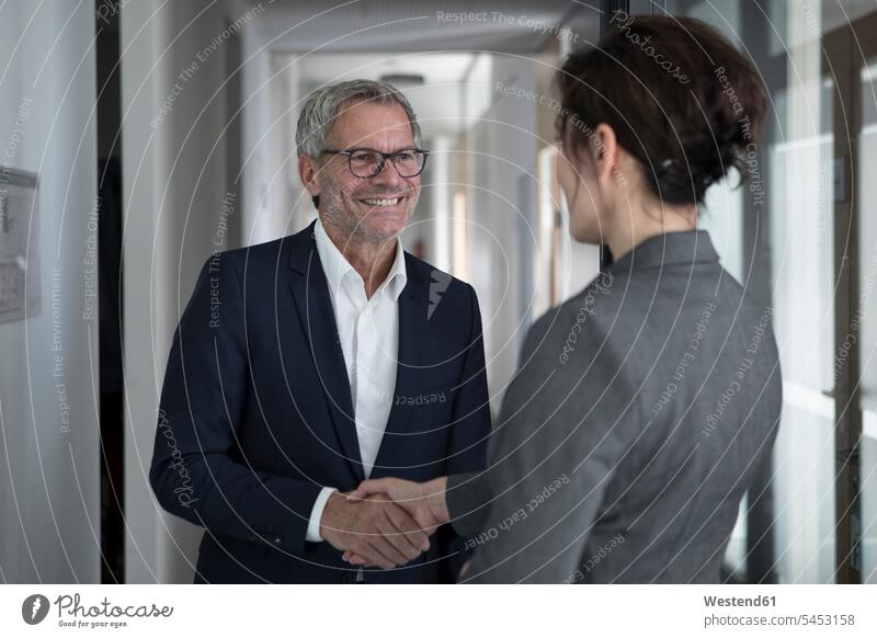 Businessman and businesswoman shaking hands in office smiling smile business partner associates business associates business partners colleagues Handclasp