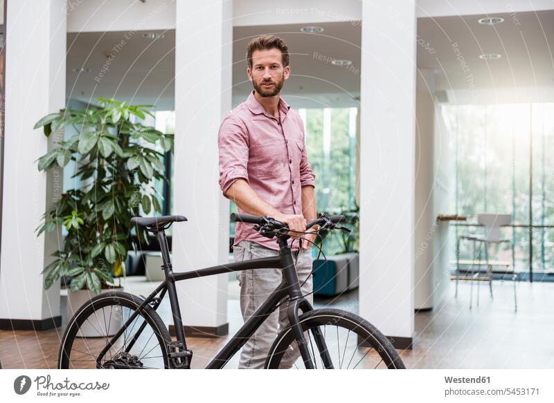 Portrait of man with bicycle in office bikes bicycles men males Adults grown-ups grownups adult people persons human being humans human beings business