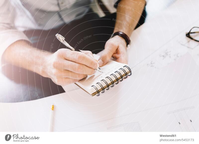 Architect taking notes at desk hand human hand hands human hands people persons human being humans human beings writing down noting architect architects office