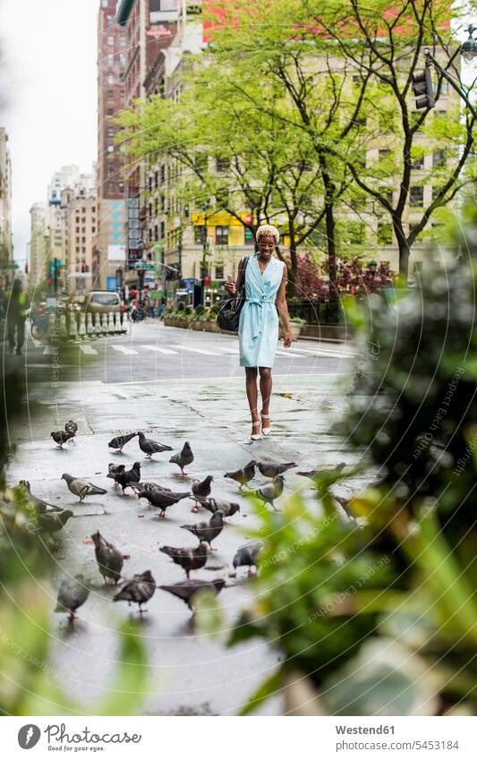 USA, New York, young blonde african-american woman walking on street, pigeons African-American Ethnicity Afro-American African American Ethnicity