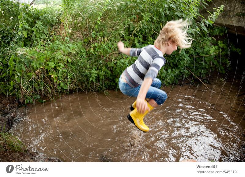 Excited girl jumping into brook Fun having fun funny Leaping brooks rivulet females girls jumps water waters body of water child children kid kids people