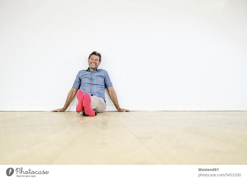 Mature man sitting on ground in empty room men males home at home thinking Sitting On The Floor Sitting On Floor carefree Seated smiling smile Adults grown-ups