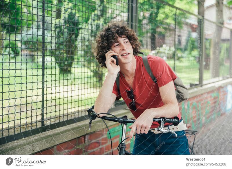 Young man with bicycle on the phone mobile phone mobiles mobile phones Cellphone cell phone cell phones call telephoning On The Telephone calling men males