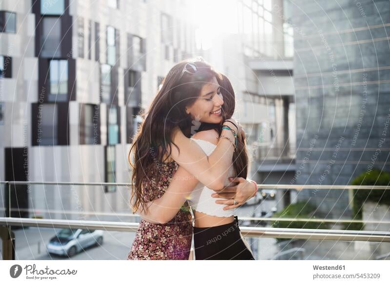 Two happy young women hugging in the city female friends smiling smile embracing embrace Embracement mate friendship happiness woman females Adults grown-ups