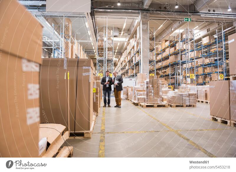 Two men talking in factory warehouse man males storehouse storage Businessman Business man Businessmen Business men speaking colleagues working At Work Adults