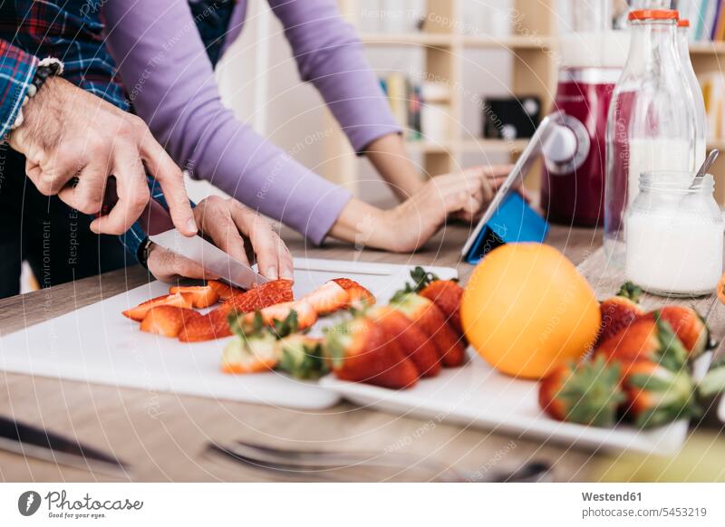 Man chopping strawberries while his girldfriend using tablet, partial view preparing Food Preparation preparing food hand human hand hands human hands