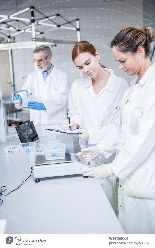 Scientists weighing samples in rain lab working At Work scales weight scales Instrument of Weight laboratory raining woman females women science sciences