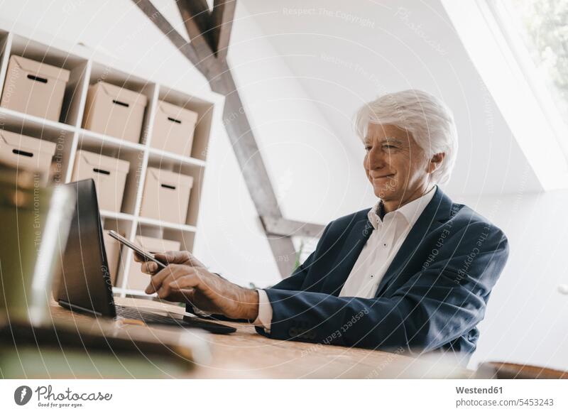 Smiling senior businessman using laptop in his office offices office room office rooms Businessman Business man Businessmen Business men workplace work place