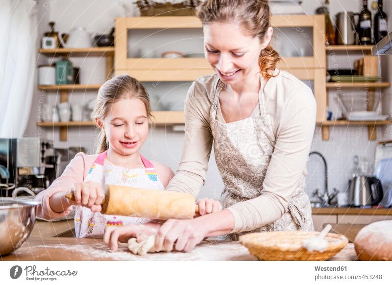 Mother and daughter baking in kitchen together smiling smile bake mother mommy mothers ma mummy mama domestic kitchen kitchens daughters parents family families