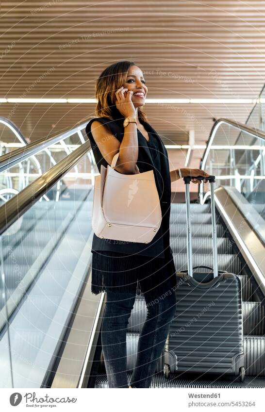 Smiling woman talking on the phone on escalator call telephoning On The Telephone calling smiling smile females women mobile phone mobiles mobile phones