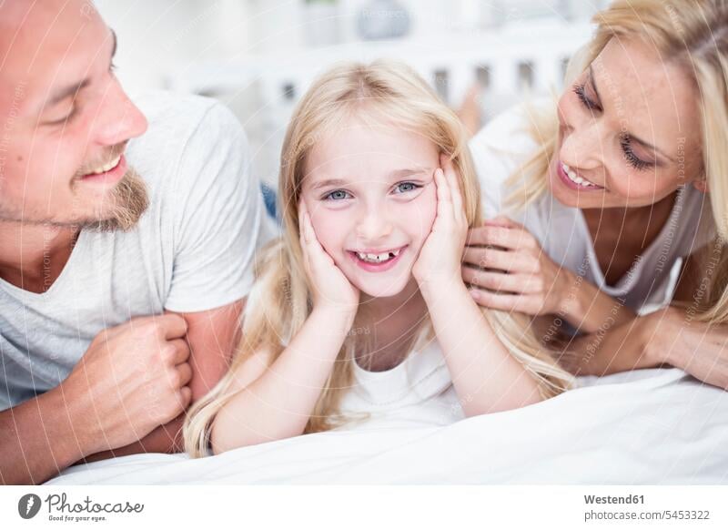 Portait of smiling girl with parents in bed beds smile family families daughter daughters people persons human being humans human beings child children home