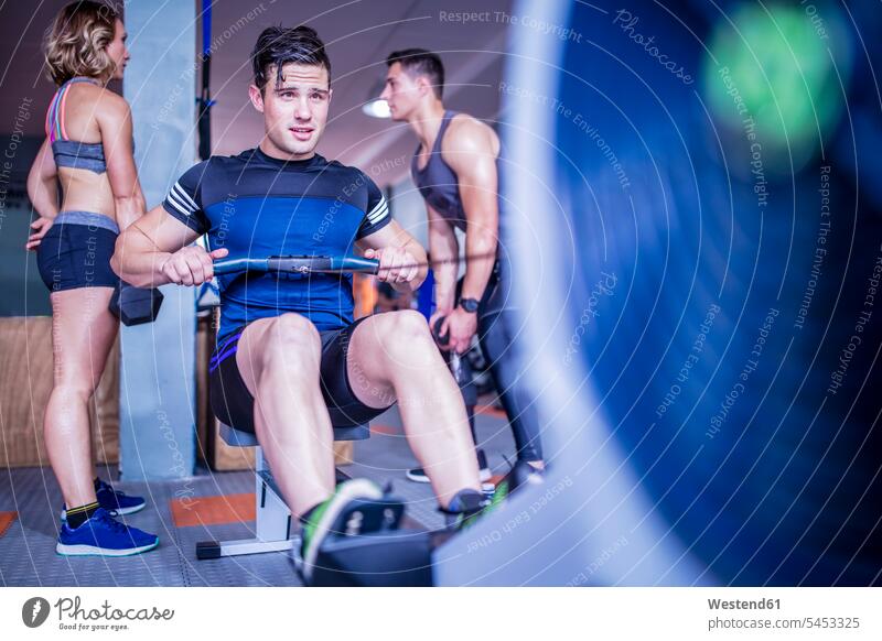 Young man exercising at rowing machine in gym exercise training practising gyms Health Club men males fitness sport sports Adults grown-ups grownups adult