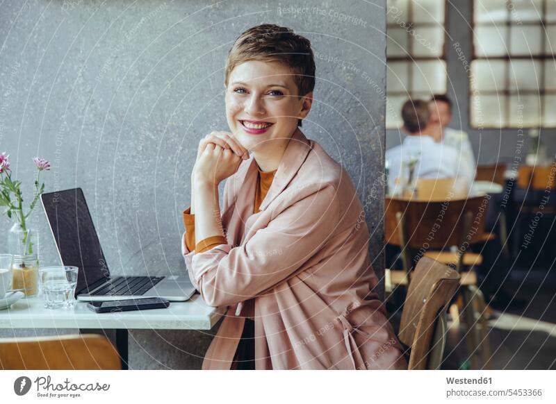 Portrait of smiling woman in cafe with laptop Laptop Computers laptops notebook smile portrait portraits females women working At Work computer computers Adults