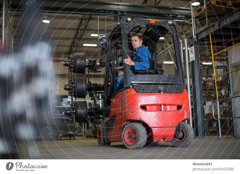 Factory working driving a fork lift in warehouse warehouseman warehouser Warehouse Worker warehousemen warehousers worker blue collar worker workers