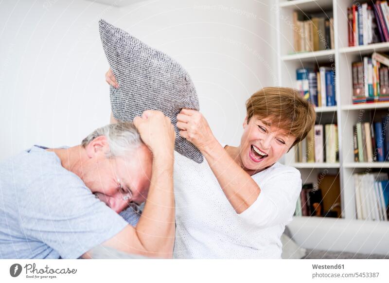 Carefree senior couple at home having a pillow fight twosomes partnership couples laughing Laughter Fun having fun funny people persons human being humans