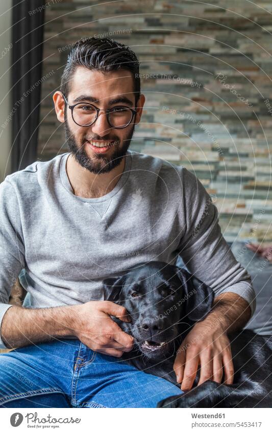Portrait of smiling young man with his dog at home dogs Canine portrait portraits men males pets animal creatures animals Adults grown-ups grownups adult people