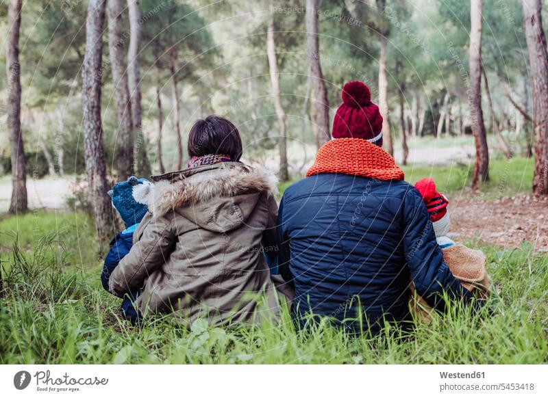 Rear view of family sitting in forest Seated families people persons human being humans human beings woods forests relaxed relaxation relaxing mid adult men
