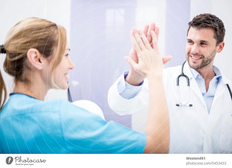 Two smiling doctors high fiving physicians smile colleagues High Five Hi-Five high-fiving High-Five Female Doctor Female Doctors healthcare and medicine medical