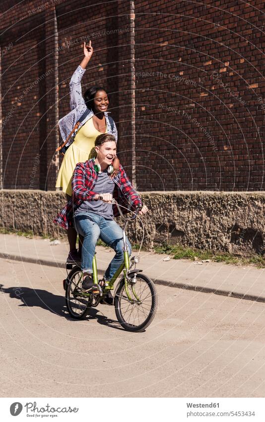 Young man riding bicycle with his girlfriend standing on rack active cheerful gaiety Joyous glad Cheerfulness exhilaration merry gay together riding bike