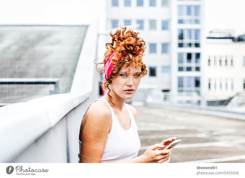 Portrait of redheaded woman holding cell phone portrait portraits mobile phone mobiles mobile phones Cellphone cell phones curly hair curls females women