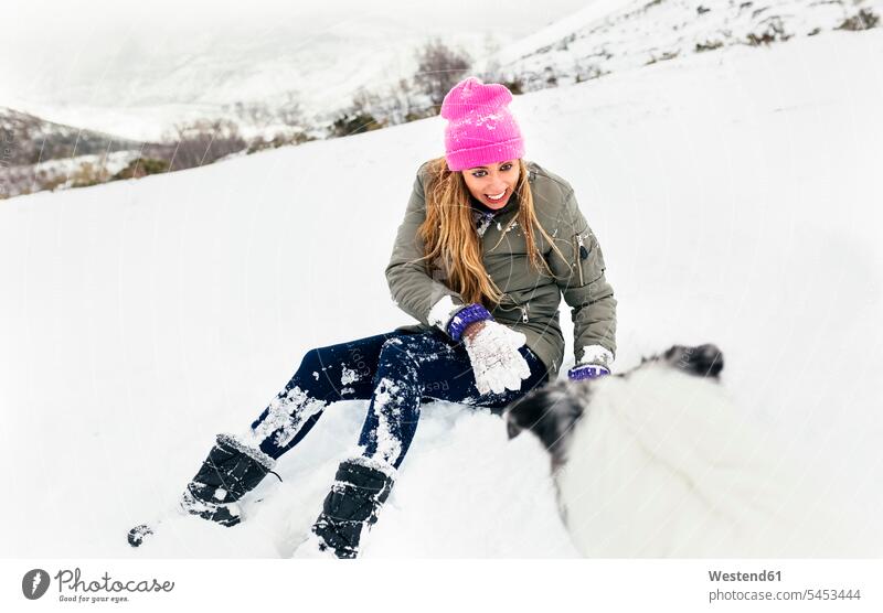 Young woman playing with her dog in the snow animal-loving fond of animals love of animals dogs Canine laughing Laughter winter hibernal pet friend