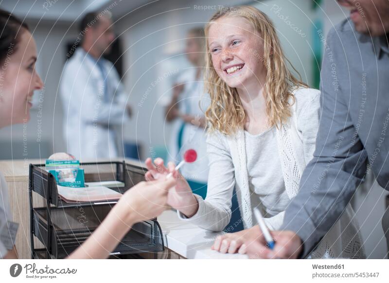 Sick girl getting lollipop from receptionist in hosptal doctor physicians doctors laughing Laughter patient clinic hospitals Medical Clinic father fathers daddy