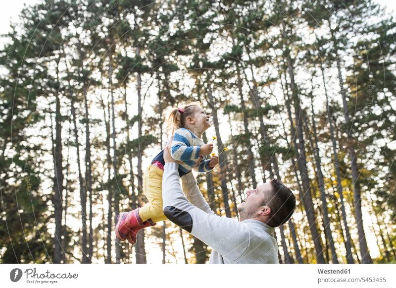 Father lifting up his daughter in forest family families happiness happy Fun having fun funny girl females girls father pa fathers daddy dads papa people