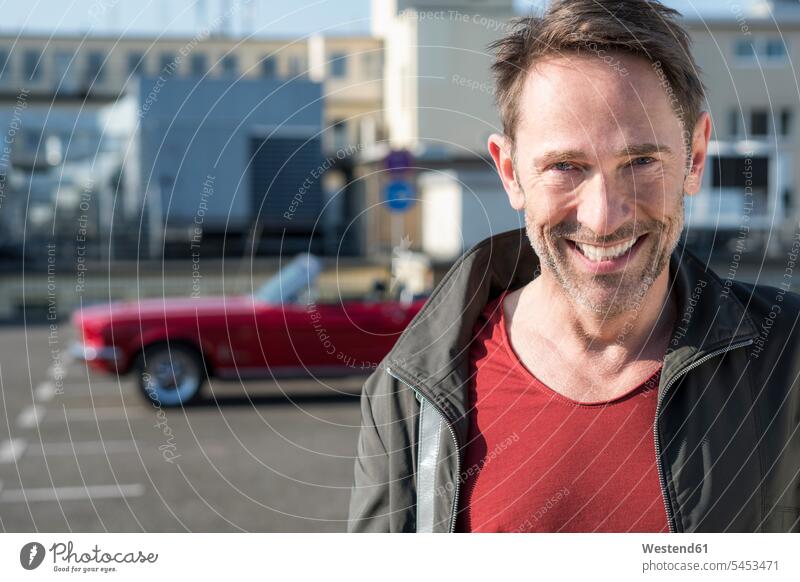Portrait of smiling mature man in front of his sports car on parking level men males Adults grown-ups grownups adult people persons human being humans