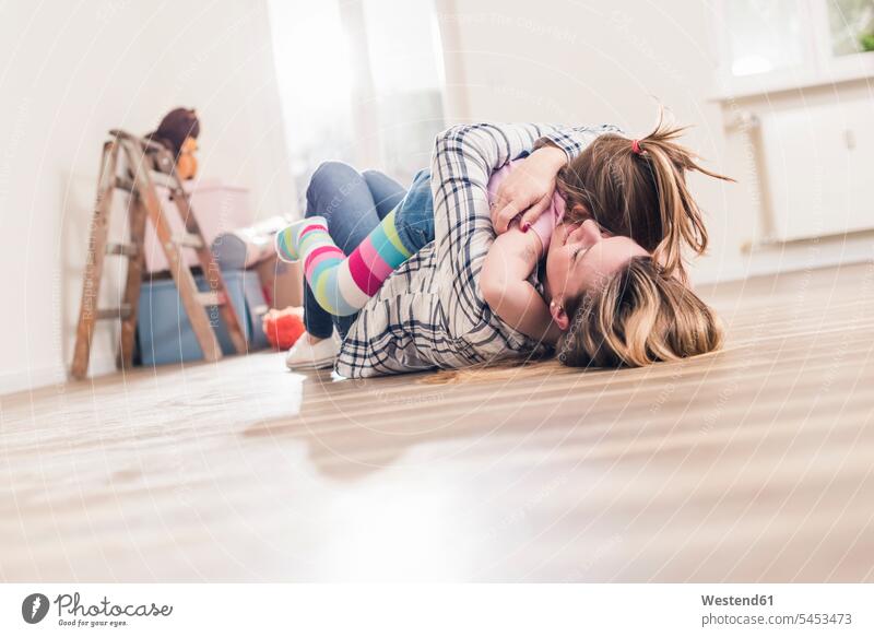 Mother and daughter hugging on the floor in new home embracing embrace Embracement lying laying down lie lying down flat flats apartment apartments daughters