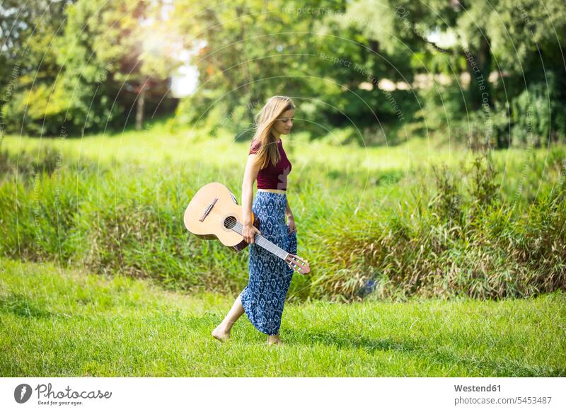 Young woan in nature with guitar walking going Grass Grasses romantic lyrical Romance natural world guitars meadow meadows young women young woman Plant Plants