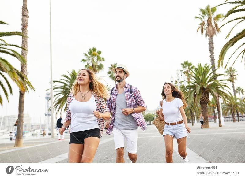 Spain, Barcelona, three tourists on the move in the city smiling smile friends mate running tourism touristic friendship leisure free time leisure time