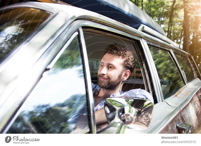 Smiling young man in car in forest woods forests automobile Auto cars motorcars Automobiles smiling smile men males motor vehicle road vehicle road vehicles