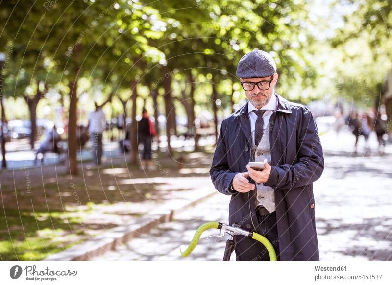 Mature businessman with bicycle and smartphone in the city mobile phone mobiles mobile phones Cellphone cell phone cell phones bikes bicycles on the phone call