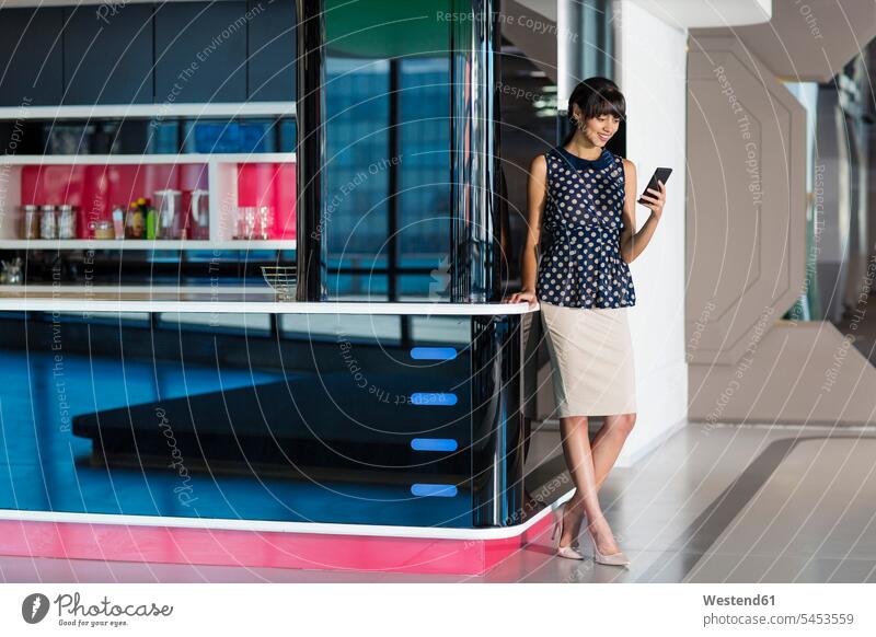 Businesswoman standing in futuristic office, using smartphone Smartphone iPhone Smartphones businesswoman businesswomen business woman business women the future