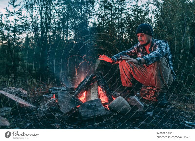 Man sitting at campfire in rural landscape Camp Fire Campfire Bonfire Seated man men males Adults grown-ups grownups adult people persons human being humans