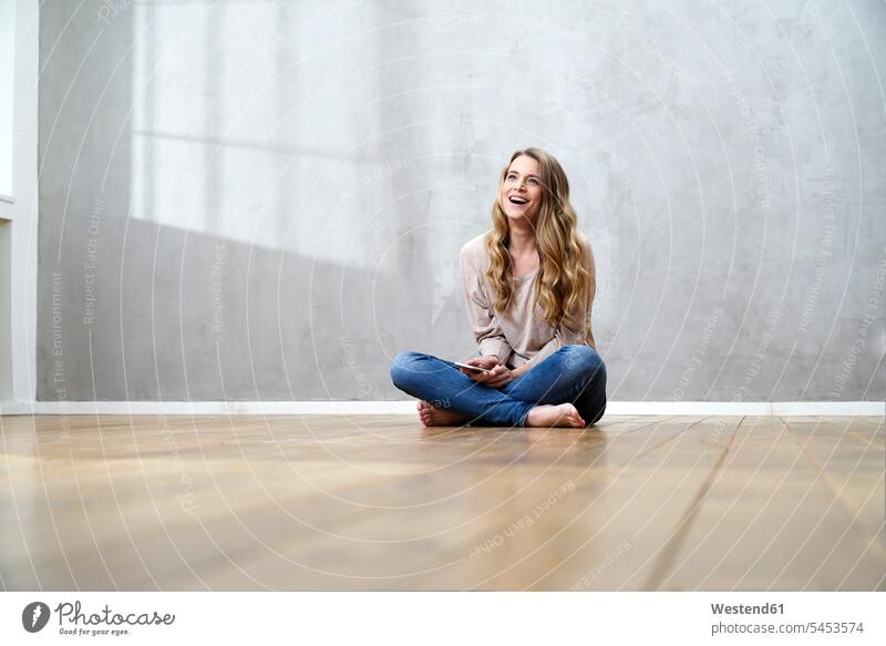 Laughing blond woman sitting on the floor with cell phone Smartphone iPhone Smartphones females women laughing Laughter mobile phone mobiles mobile phones