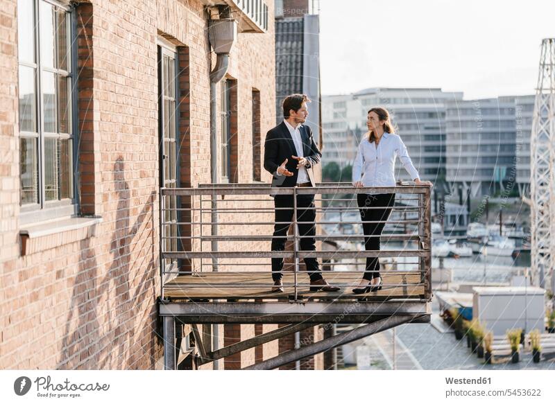Business people standing on balcony, discussing talking speaking business people businesspeople colleagues balconies business world business life discussion