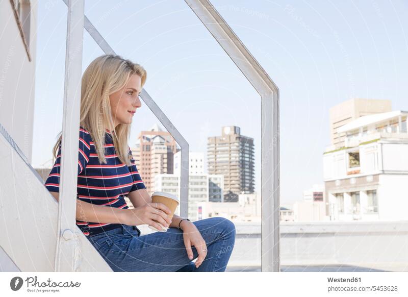 Young woman drinking coffee, sitting on stairs on a rooftop terrace females women blond blond hair blonde hair Coffee Mug Coffee Mugs roof terrace deck