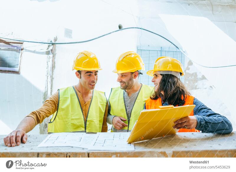 Woman showing clipboard to two construction workers on construction site builders colleagues Building Site sites Building Sites construction sites craftsman