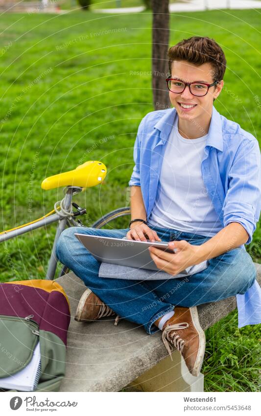 Portrait of smiling young man sitting on a bench using laptop men males Laptop Computers laptops notebook Adults grown-ups grownups adult people persons