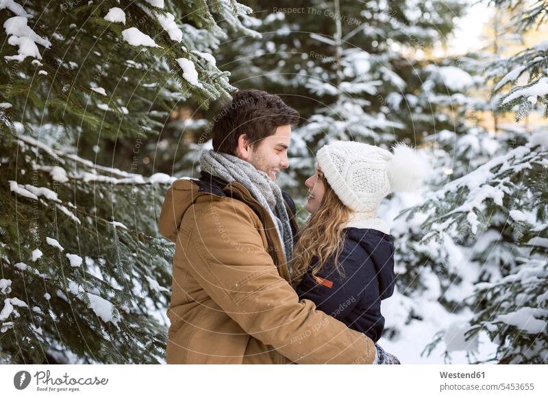 Happy young couple face to face in snow-covered winter forest twosomes partnership couples people persons human being humans human beings snow covered