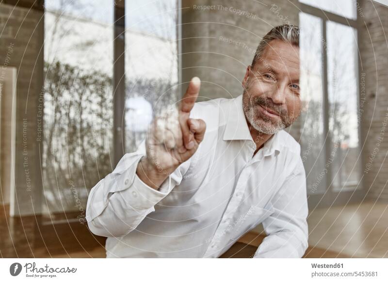 Smiling businessman pointing on glass pane smiling smile windowpane window glass window glasses windowpanes Window Pane Businessman Business man Businessmen